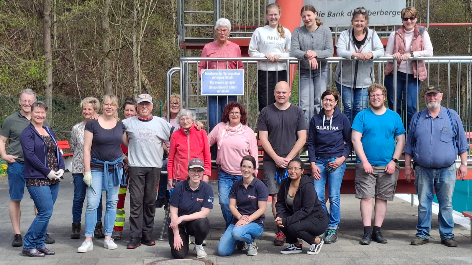 Gruppenfoto bei einem Garten-Tag am Freibad Bergneustadt: mehrere Personen stehen vor einer orangefarbenen Anlage und blicken in die Kamera.